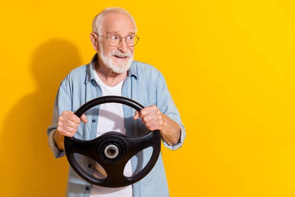 Portrait of attractive cheerful grey-haired man driving rental order copy space ad insurance isolated on vivid yellow color background - Foto, immagini