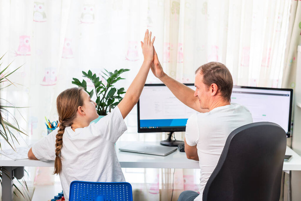 Father with teen daughter high fived while working from home during quarantine. Stay at home, work from home concept during coronavirus pandemic - Fotografie, Obrázek