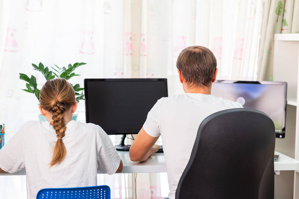 Father with teen daughter trying to work from home during quarantine. Stay at home, work from home concept during coronavirus pandemic - Photo, Image