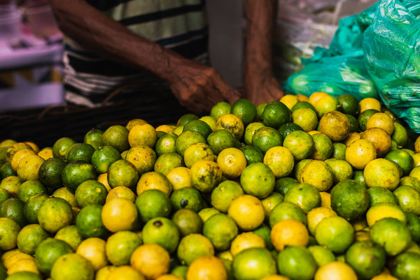 Много зеленых и желтых лимонов для продажи на прилавке на ярмарке в Сан-Хоаким. Сальвадор, Бахия, Бразилия. - Фото, изображение