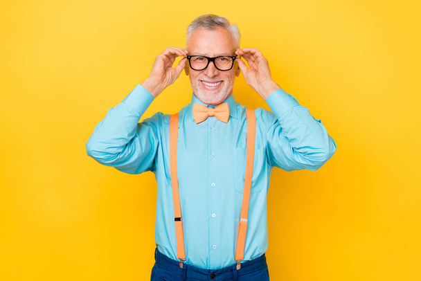 Photo of cool white hairdo man wear eyewear shirt suspenders bow tie isolated on yellow color background - Fotoğraf, Görsel