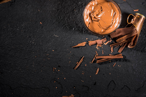 κατσαρόλα με κρέμα σοκολάτας σε μαύρη πέτρα με ροκανίδια σοκολάτας, πάνω όψη. αντίγραφο χώρου - Φωτογραφία, εικόνα