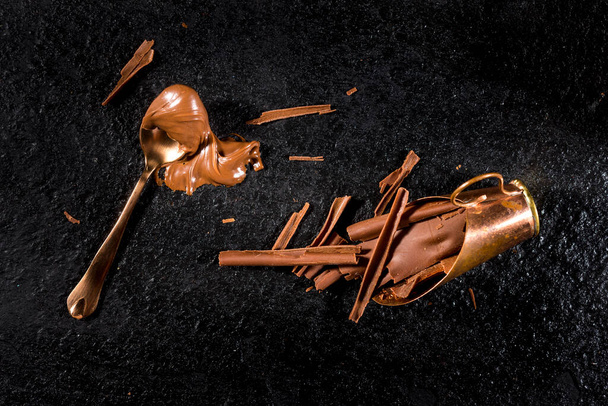 チョコレートシェービング付きブラックストーン上のスプーンチョコレートクリームトップビュー、コピースペース - 写真・画像