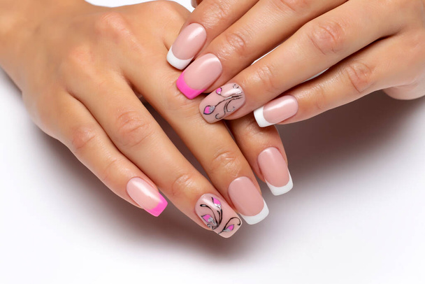 Дизайн нігтів. Французький рожево-білий манікюр з малюнками, квітами і монограмами на коротких квадратних цвяхах на білому тлі.. - Фото, зображення