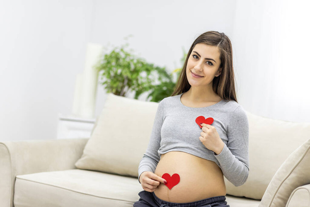 Photo of pregnant woman holding red heart in hand. - Fotó, kép