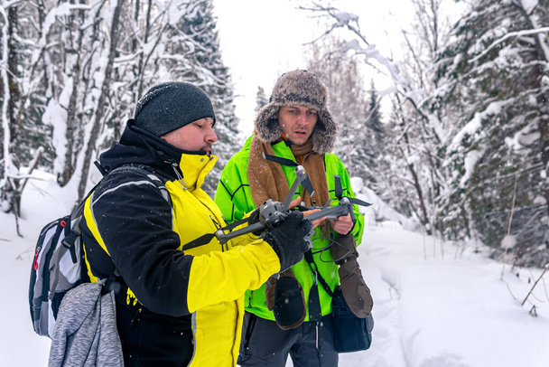 dos hombres en el bosque nevado de invierno lanzan un quadcopter - Foto, imagen