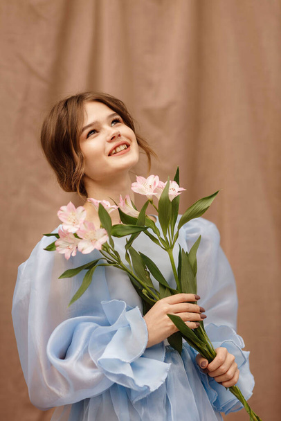 a girl in a blue dress with flowers in her hands - Photo, Image