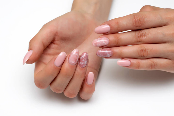 Naakt, naakt, beige, lichtroze manicure met witte vlekken, rook op de nagels, op lange ovale nagels close-up op een witte achtergrond. - Foto, afbeelding