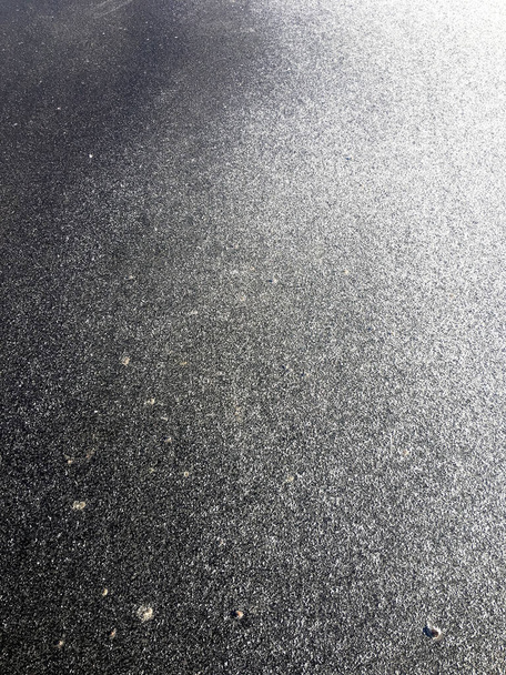 Tausta asfaltti lunta aurinkoisena, talvipäivänä. Liukas tie - Valokuva, kuva