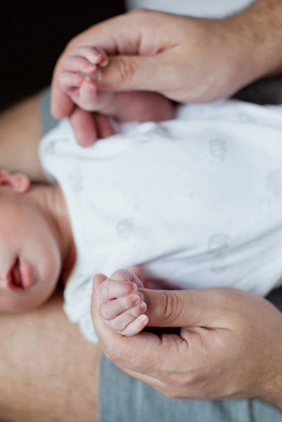 Newborn baby and father holding hands. Man holds baby hands, father love concept - 写真・画像