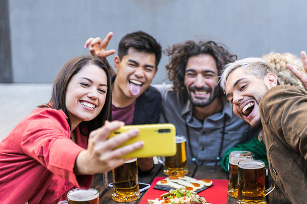 Mladí lidé se baví focení selfie v baru restaurace - Happy multiracial přátelé pití piva ve venkovním pivovaru hospoda - Fotografie, Obrázek