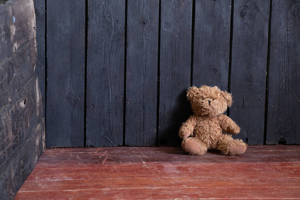 the teddy bear lies in the bedroom in the corner on the wooden floor, the bear is on the floor of the house - Photo, Image