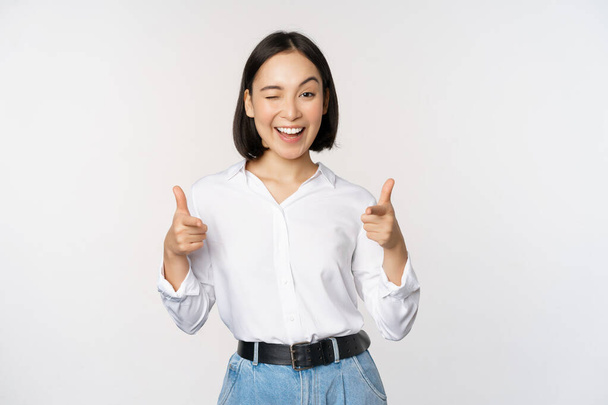 To jsi ty, gratuluju. Usmívající se atraktivní asijská žena, podnikatelka ukazuje prsty na kameru s potěšenou tváří, lichotí, zve vás, stojí nad bílým pozadím. - Fotografie, Obrázek