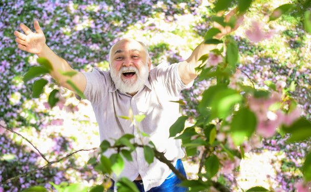 Come with me. Human emotions and expressions. Very old man portrait. thinking about youth in park or garden. happy man under spring sakura blossom. senior man looking up. good memories of past - Foto, Imagen