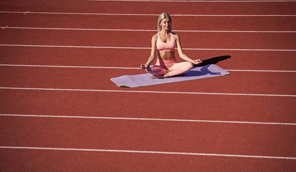 sport woman in sportswear practicing yoga on stadium running track before training fitness, meditation - Foto, afbeelding