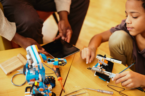 Um avô e um neto a fazer um robô juntos em casa. Educação em robótica e eletrônica. - Foto, Imagem