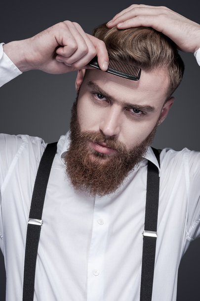 Bearded man combing his hair - Фото, зображення