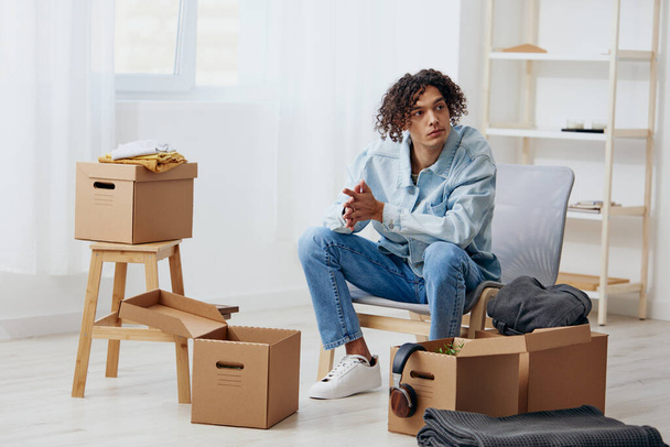 A young man unpacking things from boxes in the room interior. High quality photo - Photo, Image
