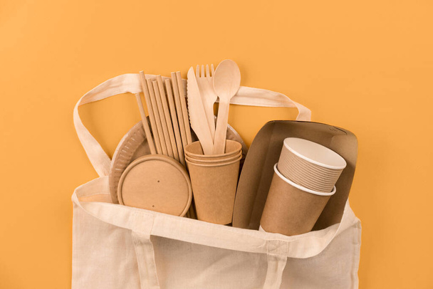 Vaisselle en papier écologique - gobelets et contenants kraft en papier alimentaire dans un sac en coton sur fond orange avec espace de copie. La nourriture de rue emporte les ustensiles en papier - tasses, assiettes, pailles à boire. Maquette - Photo, image