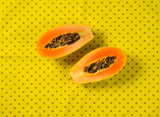 sezione trasversale di papaia isolata su sfondo tessuto giallo, vista dall'alto. - Foto, immagini