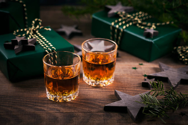 Whiskey, brandy or liquor shot and Christmas decorations on wooden background. Christmas holidays mood concept. - Foto, Imagen
