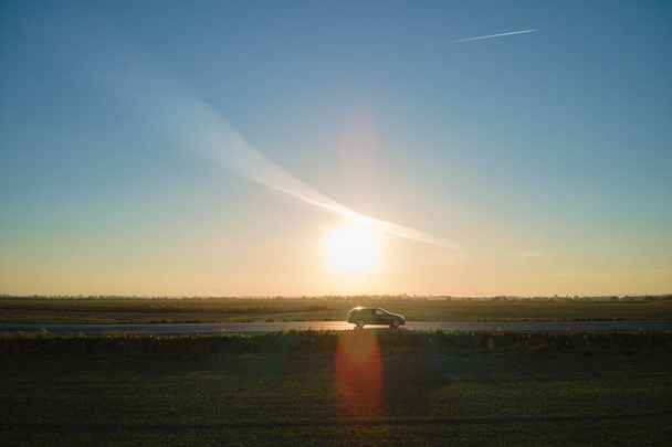 Widok z lotu ptaka na międzymiastową drogę z zamazanym szybkim samochodem o zachodzie słońca. Widok z góry z drona ruchu drogowego w godzinach wieczornych - Zdjęcie, obraz