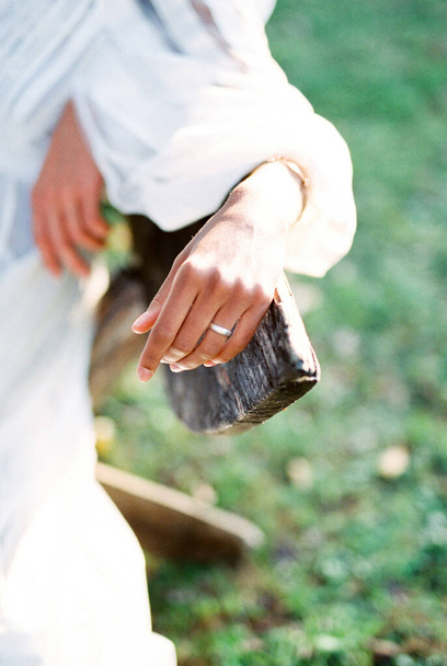 Woman hand with a ring on her finger lies on the back of a wooden bench. Close-up. High quality photo - Photo, Image