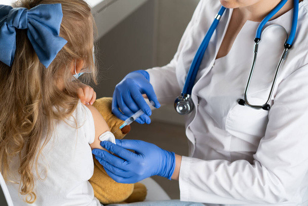 lasten rokottaminen, pieni tyttö lääkärin vastaanotolla, injektio käsivarteen, conce. - Valokuva, kuva