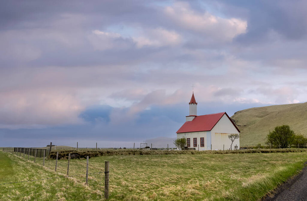 Kleine historische kerk op het platteland van IJsland met dramatische hemel. - Foto, afbeelding