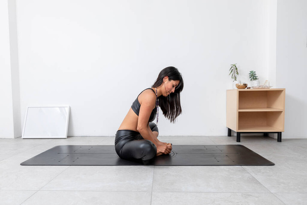 Bağlı Açı pozu veren genç İspanyol kadın, yoga stüdyosunda spor kıyafetleri giyiyor. - Fotoğraf, Görsel