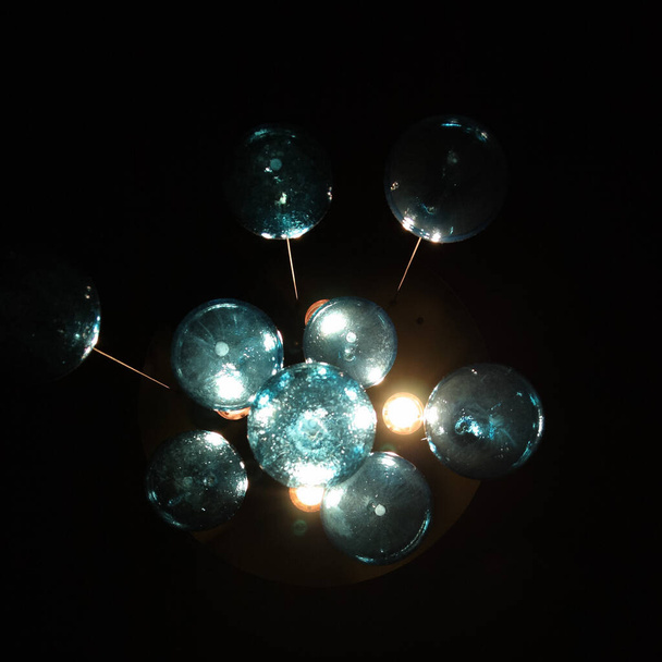 Artistic chandelier with cyan orbs. - 写真・画像