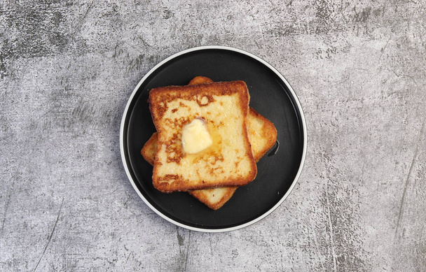 French toast with melting butter on a round plate on a dark gray background. Top view, flat lay - Foto, immagini