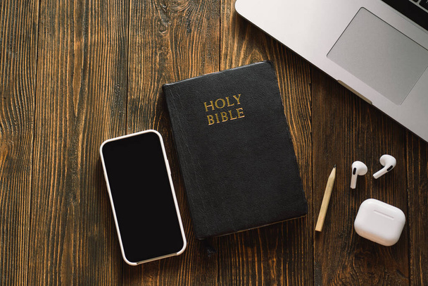 Pazar günü kilise online yeni normal konsept. İncil, cep telefonu ve ahşap bir arka planda kulaklık.. - Fotoğraf, Görsel
