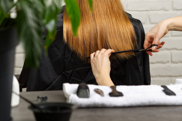 Kobieca pielęgnacja włosów. Fryzjer podejmowania fryzurę do młodej dziewczyny w salonie piękności dziecka. - Zdjęcie, obraz