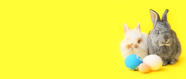 Cute rabbits and Easter eggs on yellow background with space for text - Photo, Image