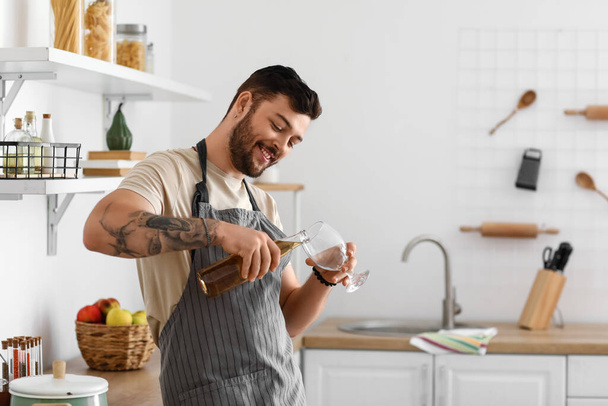 Young bearded man pouring beer into glass in kitchen - Photo, Image