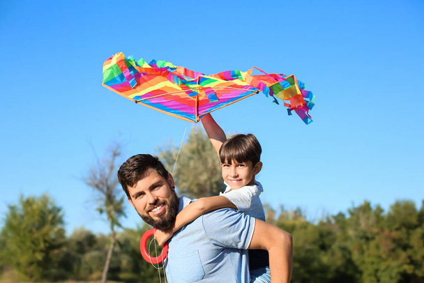 Счастливый отец таскает своего маленького сына с воздушным змеем в парке - Фото, изображение