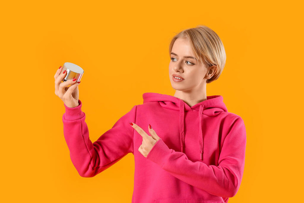 Young woman pointing at wireless portable speaker on color background - Foto, Bild