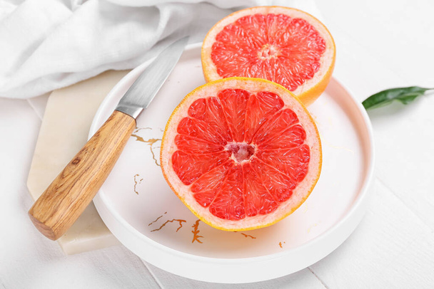 Plate with tasty cut grapefruit on wooden background - Photo, Image