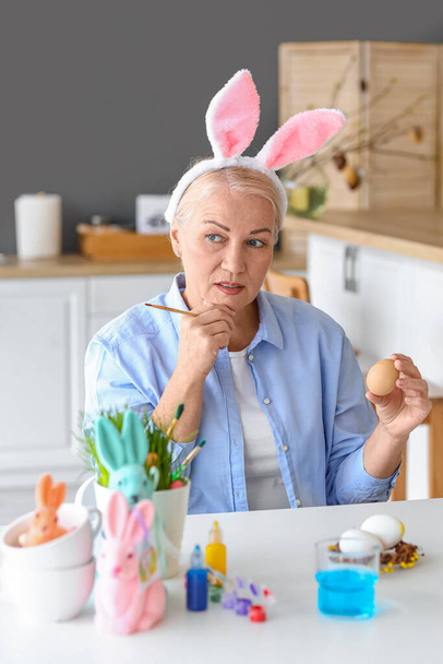 Mature woman painting Easter eggs at home - Photo, Image