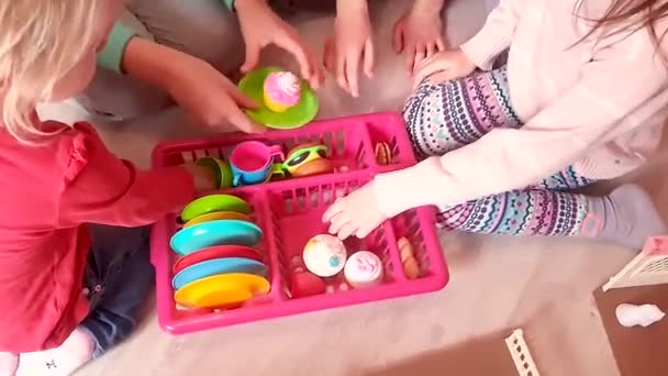 Kleine kinderen spelen in de kinderkeuken en verzamelen borden. - Video