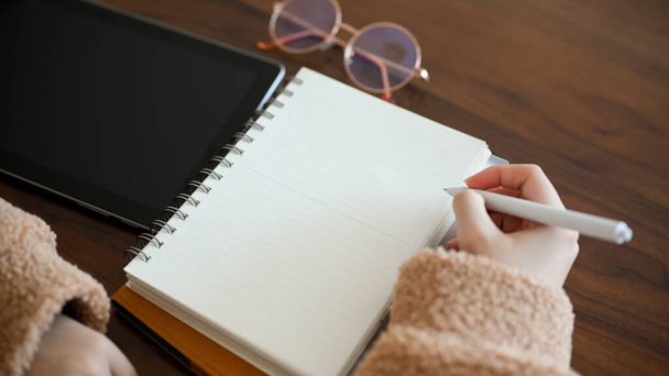 Close-up, Una estudiante universitaria escribiendo algo en el bloc de notas, tomando notas en cuaderno espiral. - Foto, Imagen