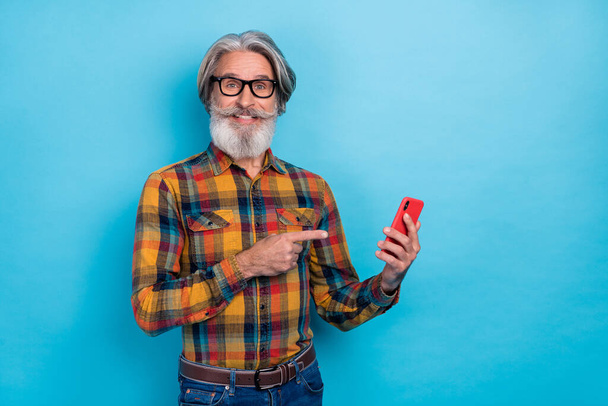 Photo of aged man indicate finger empty space ad promo decision suggest proposition isolated over blue color background. - Photo, image