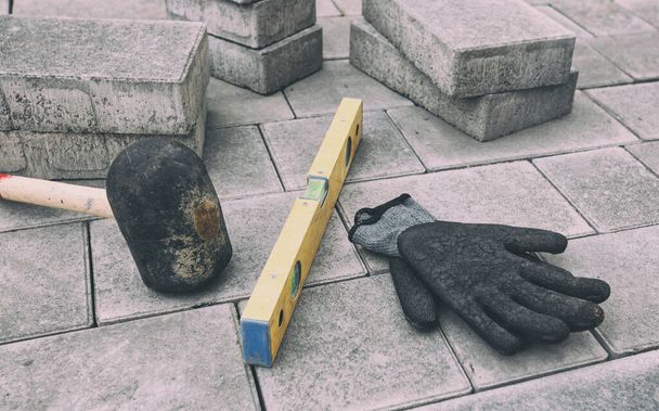 Gloves, hammer and building level on paving stone - Foto, Imagen