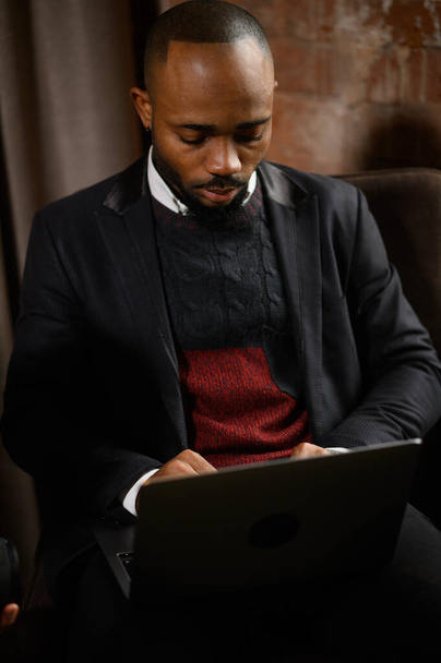 egy fiatal törekvő afro-amerikai befektető dolgozik egy számítógépen, elemzi az értékpapírpiacot.  - Fotó, kép