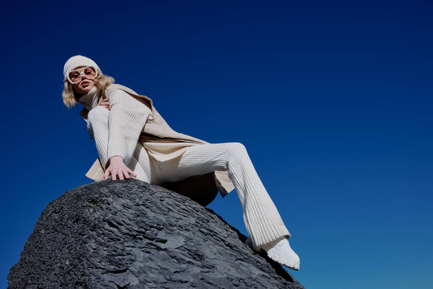 mujer joven en ropa de otoño se encuentra en un paisaje de roca cielo azul relajación. Foto de alta calidad - Foto, Imagen