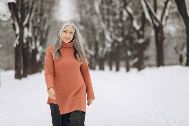 冬の雪の天気を背景に笑顔のニットセーターに白髪のシニア女性の肖像画 - 写真・画像