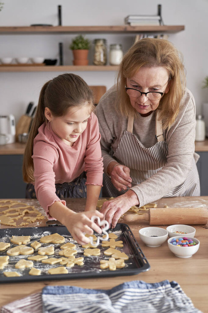 Caucasian of grandmother help her granddaughter bake cookies  - Photo, Image