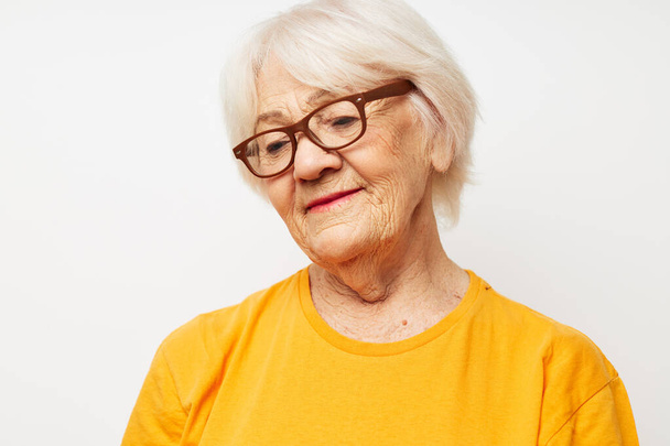 emotional elderly woman in casual t-shirt and glasses light background - Fotografie, Obrázek