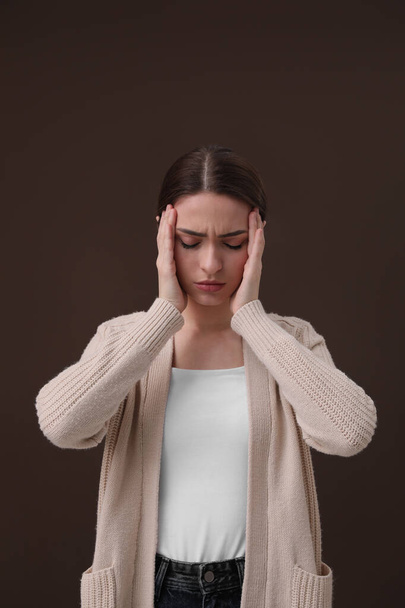 Woman suffering from headache on brown background. Cold symptoms - Photo, Image